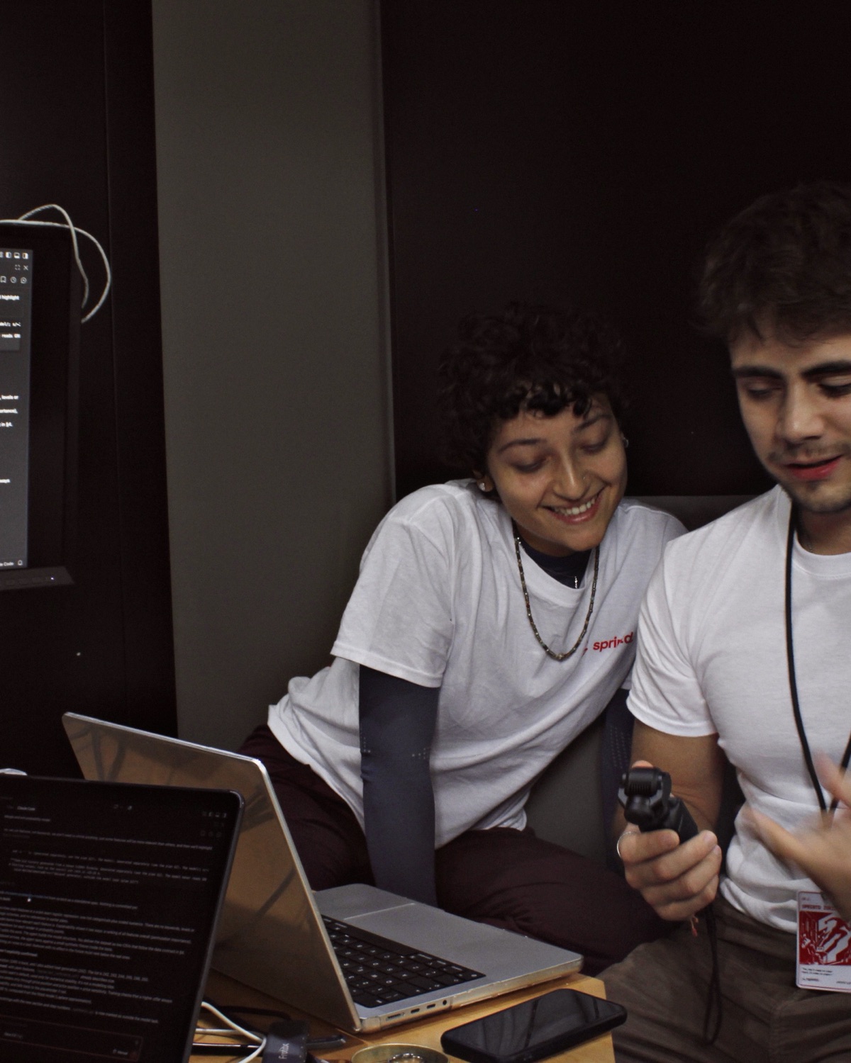 Two builders in sprintd shirts laughing over a laptop during a sprint.